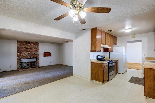 2100 E Linden Ave, Fresno, CA 93725 - kitchen with stainless steel range with gas stovetop, freestanding refrigerator, a textured ceiling, light countertops, and light floors
