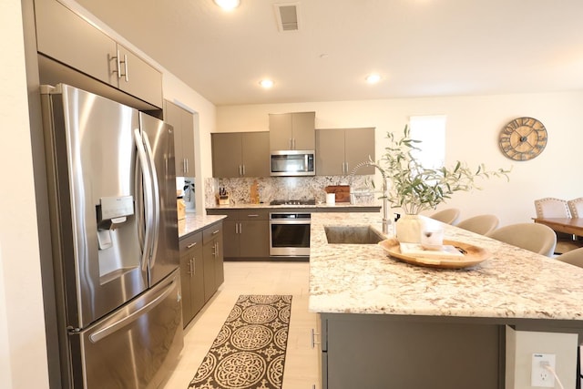 4090 Buckingham Ave, Clovis, CA 93619 - kitchen with stainless steel appliances, gray cabinetry, a sink, tasteful backsplash, and light stone countertops