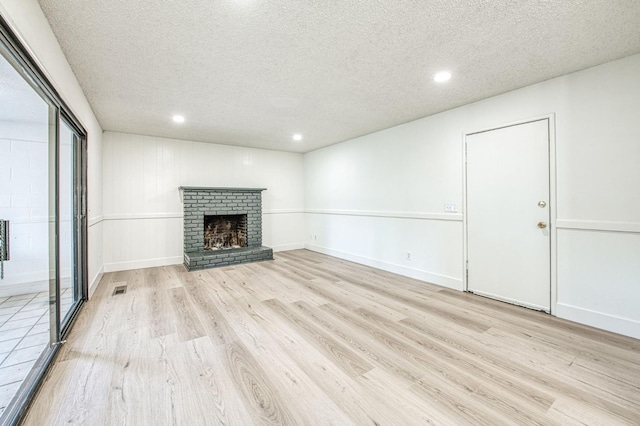 1448 N Helm Ave, Fresno, CA 93727 - unfurnished living room with light wood-type flooring, a textured ceiling, recessed lighting, a fireplace, and baseboards