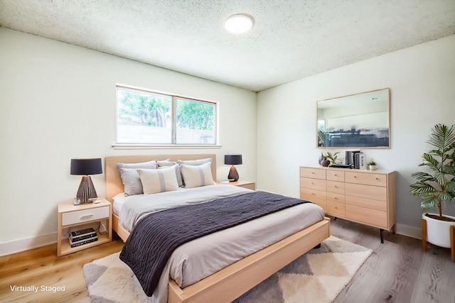 1448 N Helm Ave, Fresno, CA 93727 - bedroom with light wood-style floors, a textured ceiling, and baseboards