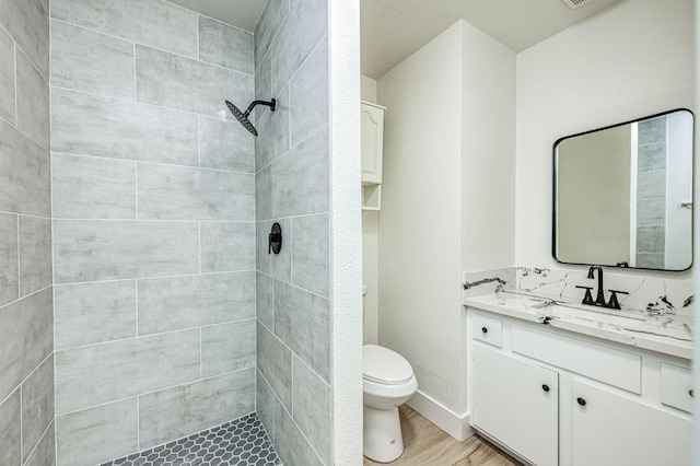 1448 N Helm Ave, Fresno, CA 93727 - full bathroom with vanity, toilet, a tile shower, and wood finished floors
