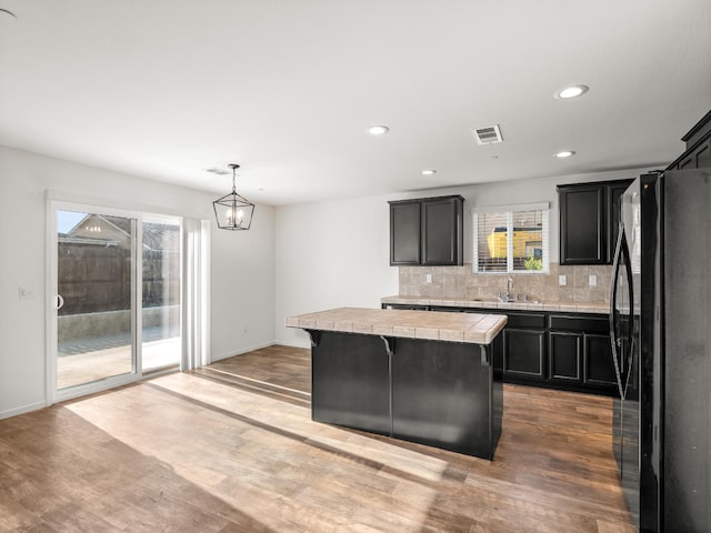703 Tulip Cir, Dinuba, CA 93618 - kitchen with freestanding refrigerator, tile countertops, a sink, plenty of natural light, and recessed lighting