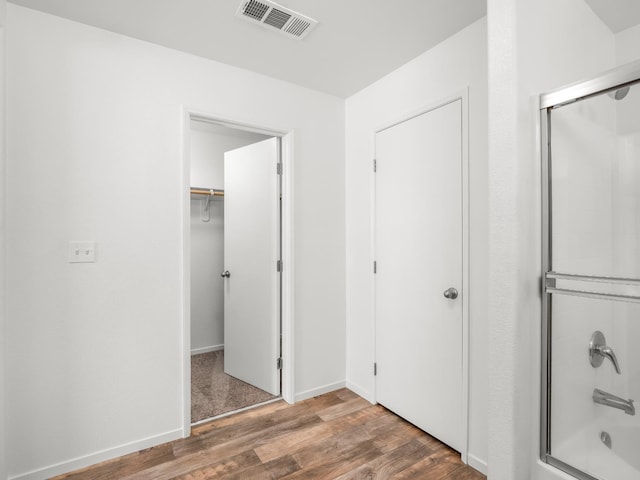 703 Tulip Cir, Dinuba, CA 93618 - full bathroom with wood finished floors, bath / shower combo with glass door, and a walk in closet