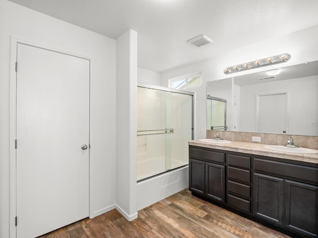 703 Tulip Cir, Dinuba, CA 93618 - full bath featuring double vanity, shower / bath combination with glass door, and wood finished floors