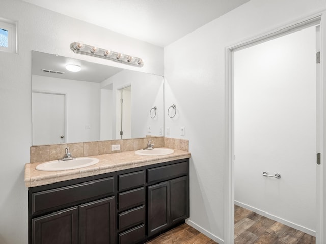 703 Tulip Cir, Dinuba, CA 93618 - bathroom featuring double vanity, wood finished floors, and baseboards