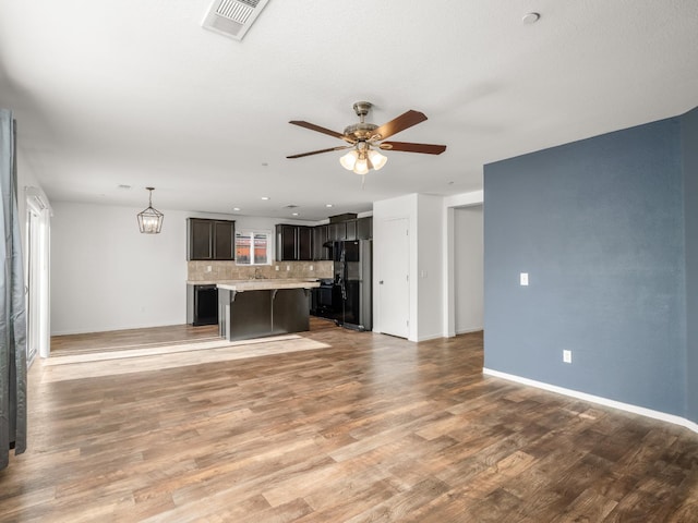 703 Tulip Cir, Dinuba, CA 93618 - unfurnished living room featuring a ceiling fan, baseboards, and light wood-type flooring