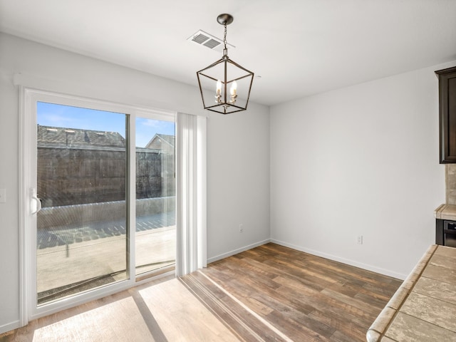 703 Tulip Cir, Dinuba, CA 93618 - unfurnished dining area with wood finished floors, a chandelier, and baseboards