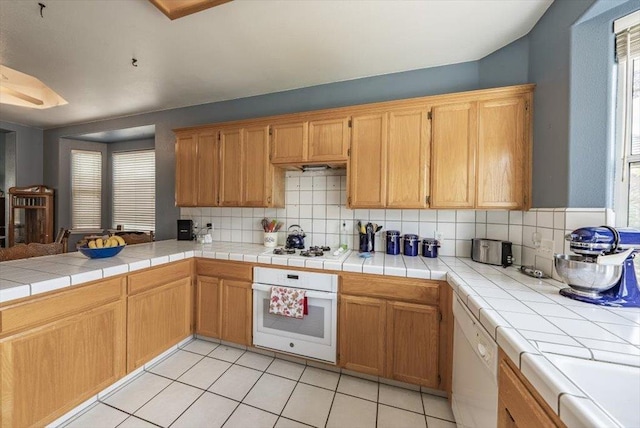 3159 Cedar Creek Ln, Madera, CA 93637 - kitchen featuring white appliances, backsplash, light tile patterned flooring, and a peninsula