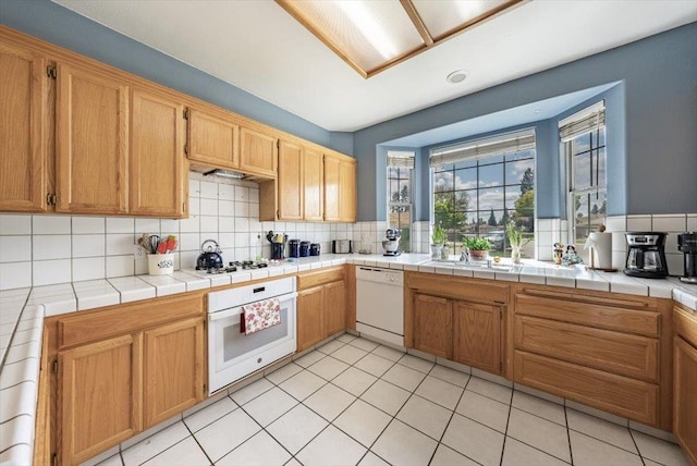 3159 Cedar Creek Ln, Madera, CA 93637 - kitchen with white appliances, decorative backsplash, light tile patterned floors, and tile counters