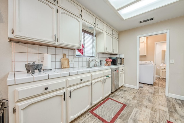 1183 E Dinuba Ave, Fresno, CA 93725 - kitchen featuring washer / dryer, stainless steel appliances, tasteful backsplash, a sink, and light wood-style flooring