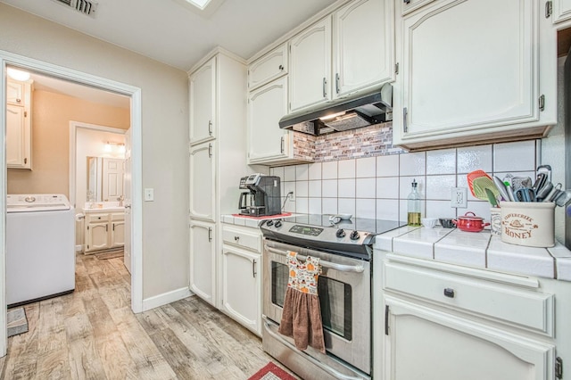 1183 E Dinuba Ave, Fresno, CA 93725 - kitchen with washer / clothes dryer, stainless steel electric stove, under cabinet range hood, tile counters, and light wood-style floors