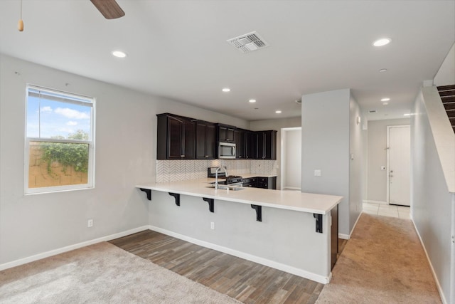2830 Leanna Ave, Fresno, CA 93737 - kitchen with appliances with stainless steel finishes, a kitchen bar, a peninsula, light countertops, and baseboards