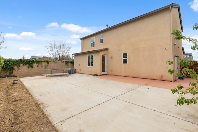 2830 Leanna Ave, Fresno, CA 93737 - rear view of property featuring a trampoline, a fenced backyard, stucco siding, a patio, and central AC