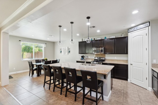 1697 Whiteash Ave, Clovis, CA 93619 - kitchen featuring appliances with stainless steel finishes, a sink, light tile patterned flooring, a breakfast bar area, and a center island with sink
