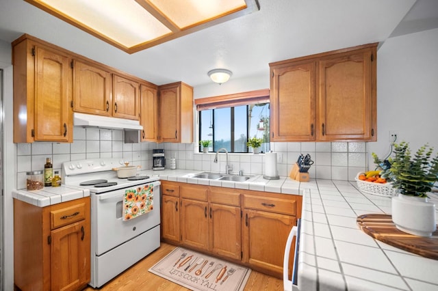 18118 Rd 26, Madera, CA 93638 - kitchen with white electric stove, a sink, under cabinet range hood, and tasteful backsplash