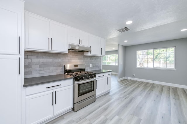 153 Birch, Fresno, CA 93650 - kitchen featuring stainless steel gas range oven, under cabinet range hood, dark countertops, backsplash, and baseboards
