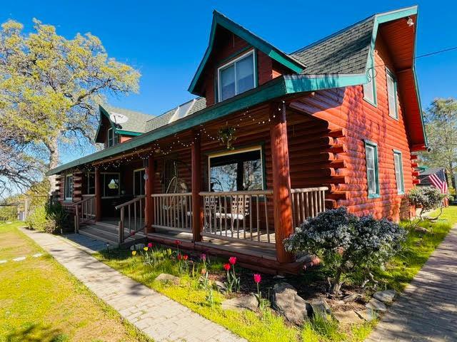 30670 Sentinel Dr, Coarsegold, CA 93614 - view of front of house with log siding, covered porch, a gambrel roof, and a shingled roof