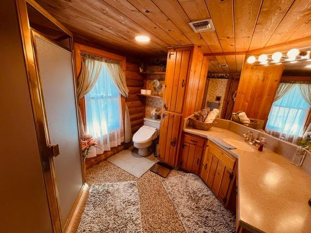 30670 Sentinel Dr, Coarsegold, CA 93614 - bathroom with wooden ceiling, vanity, toilet, an enclosed shower, and log walls