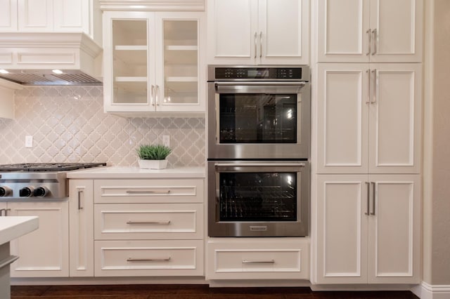 2138 El Paso Ave, Clovis, CA 93611 - kitchen featuring appliances with stainless steel finishes, tasteful backsplash, glass insert cabinets, light countertops, and wall chimney range hood