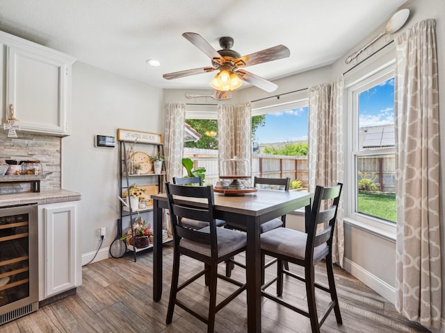 279 Lily Ave, Sanger, CA 93657 - dining space with beverage cooler, baseboards, light wood-style floors, a ceiling fan, and a bar