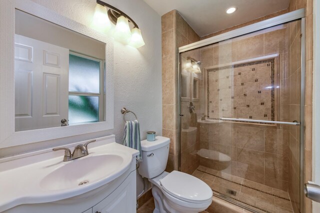 8259 N College Ave, Fresno, CA 93711 - bathroom featuring toilet, vanity, a shower stall, a textured wall, and recessed lighting