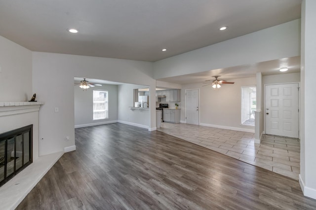 8259 N College Ave, Fresno, CA 93711 - unfurnished living room featuring a ceiling fan, a glass covered fireplace, recessed lighting, baseboards, and wood finished floors