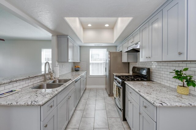 8259 N College Ave, Fresno, CA 93711 - kitchen featuring stainless steel appliances, a sink, under cabinet range hood, a tray ceiling, and backsplash