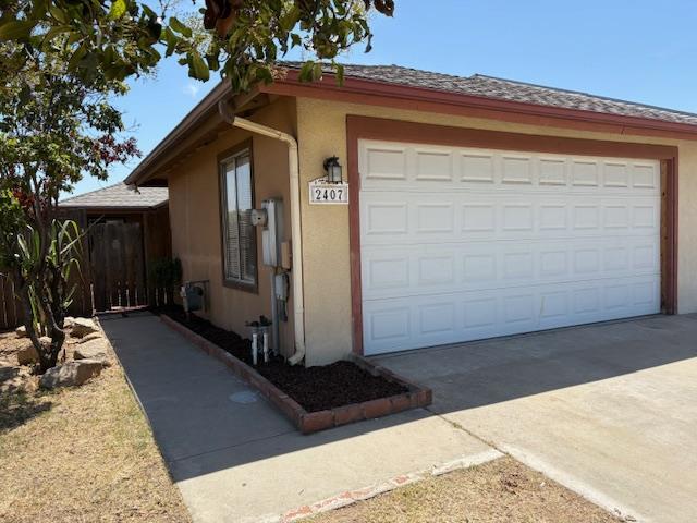 2407 W Carmen Ave, Fresno, CA 93728 - view of front of property with a garage, stucco siding, and driveway