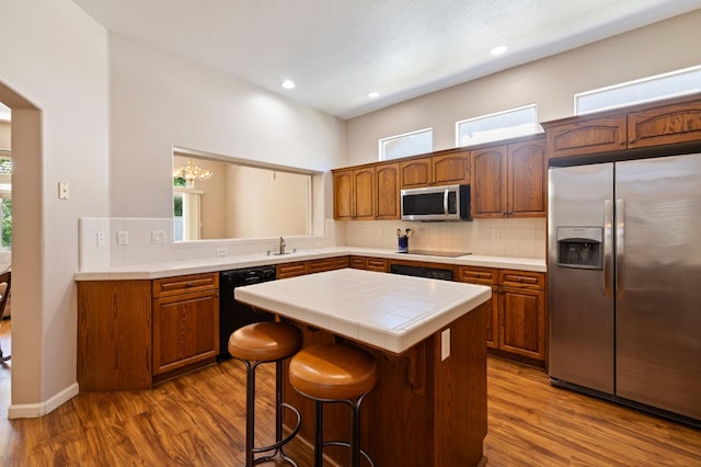 5125 N Via Amore, Fresno, CA 93711 - kitchen featuring black appliances, tile counters, a center island, dark wood finished floors, and tasteful backsplash