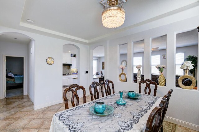 2701 Glade Ave, Madera, CA 93637 - dining area with a raised ceiling, baseboards, arched walkways, light tile patterned floors, and a chandelier