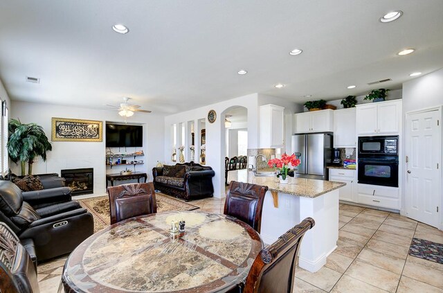 2701 Glade Ave, Madera, CA 93637 - dining area featuring ceiling fan, arched walkways, recessed lighting, light tile patterned flooring, and a tiled fireplace