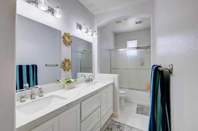 2701 Glade Ave, Madera, CA 93637 - full bathroom featuring toilet, double vanity, and bath / shower combo with glass door