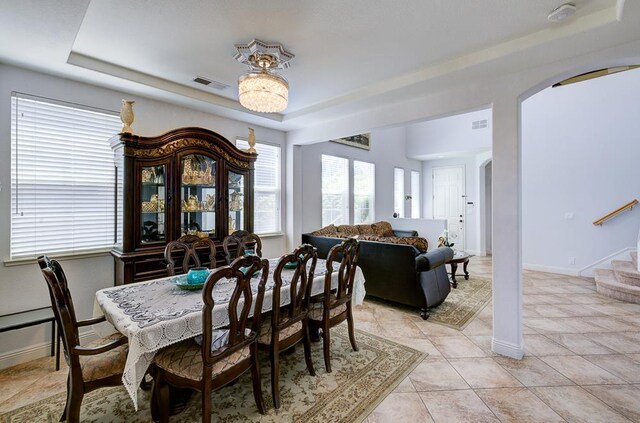 2701 Glade Ave, Madera, CA 93637 - dining space featuring arched walkways, a raised ceiling, light tile patterned floors, and baseboards