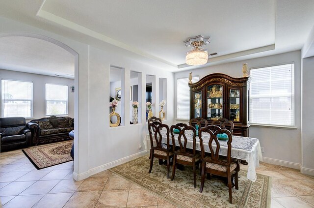 2701 Glade Ave, Madera, CA 93637 - dining space featuring a raised ceiling, arched walkways, light tile patterned floors, and baseboards