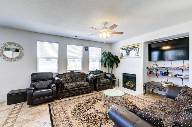2701 Glade Ave, Madera, CA 93637 - living room featuring a ceiling fan, light tile patterned flooring, a tiled fireplace, and baseboards