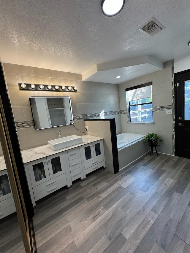 6762 N Knoll Ave, Fresno, CA 93711 - full bath featuring a textured ceiling, vanity, a garden tub, and wood finished floors