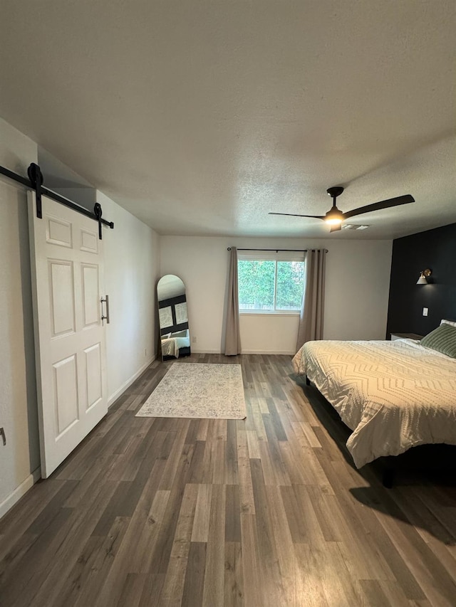 6762 N Knoll Ave, Fresno, CA 93711 - bedroom featuring a barn door, dark wood-style floors, a ceiling fan, baseboards, and a textured ceiling