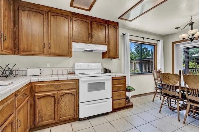 42939 Scenic Dr, Oakhurst, CA 93644 - kitchen with under cabinet range hood, white electric range oven, tile counters, and light tile patterned floors