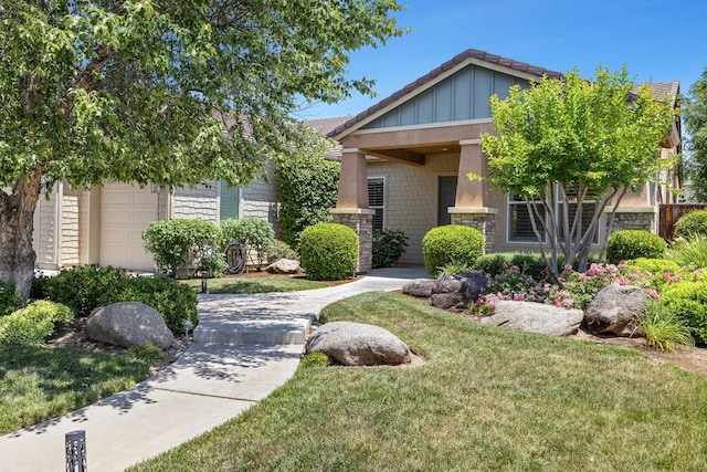 1977 N Dara Ave, Clovis, CA 93619 - view of front of home with stone siding, a front yard, board and batten siding, and a garage