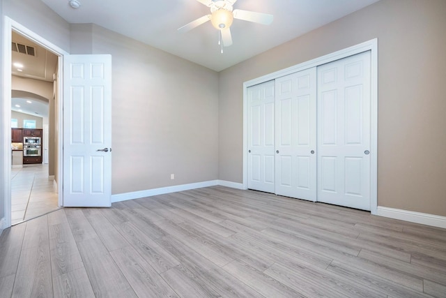 1977 N Dara Ave, Clovis, CA 93619 - unfurnished bedroom featuring light wood-style floors, baseboards, a closet, and arched walkways