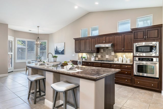 1977 N Dara Ave, Clovis, CA 93619 - kitchen featuring stainless steel appliances, light tile patterned floors, under cabinet range hood, a breakfast bar area, and a kitchen island with sink
