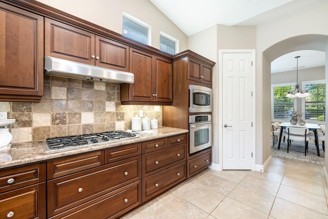 1977 N Dara Ave, Clovis, CA 93619 - kitchen featuring appliances with stainless steel finishes, under cabinet range hood, arched walkways, a chandelier, and backsplash