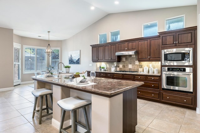1977 N Dara Ave, Clovis, CA 93619 - kitchen with appliances with stainless steel finishes, light tile patterned floors, a kitchen bar, dark brown cabinets, and recessed lighting