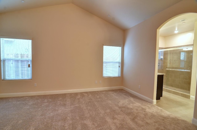 2129 La Canada Ave, Clovis, CA 93619 - unfurnished bedroom with vaulted ceiling, arched walkways, light carpet, baseboards, and ensuite bath