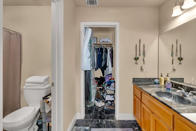 704 Rancho Vista Dr, Atwater, CA 95301 - bathroom with marble look tiles, vanity, baseboards, toilet, and a walk in closet
