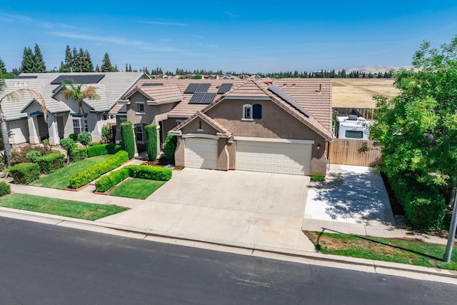2721 Stuart Ave, Clovis, CA 93611 - traditional-style home featuring stucco siding, concrete driveway, roof mounted solar panels, a tile roof, and a garage