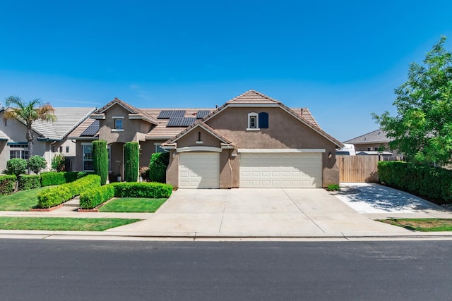 2721 Stuart Ave, Clovis, CA 93611 - traditional-style home with stucco siding, roof mounted solar panels, concrete driveway, an attached garage, and a tile roof