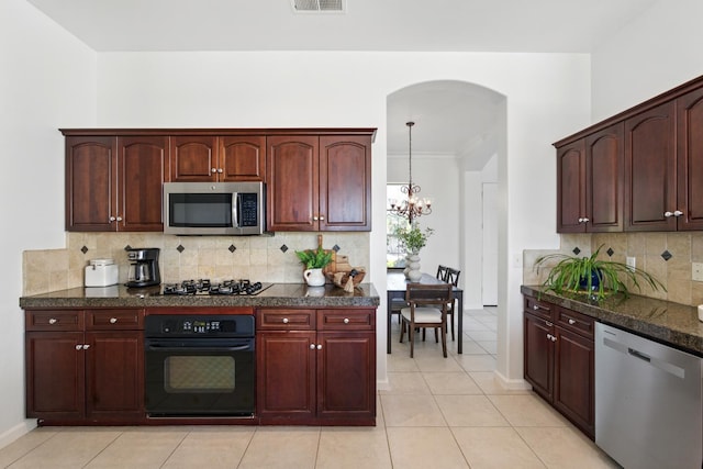 2721 Stuart Ave, Clovis, CA 93611 - kitchen featuring appliances with stainless steel finishes, arched walkways, a chandelier, tasteful backsplash, and light tile patterned floors