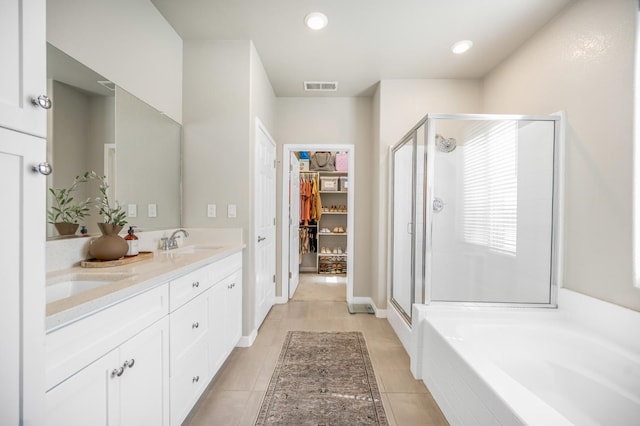 6085 E Homan Ave, Fresno, CA 93727 - full bath with a stall shower, double vanity, a garden tub, a walk in closet, and tile patterned flooring