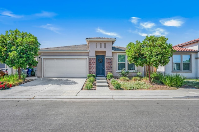 6085 E Homan Ave, Fresno, CA 93727 - view of front of house featuring a garage, stucco siding, driveway, a tiled roof, and brick siding